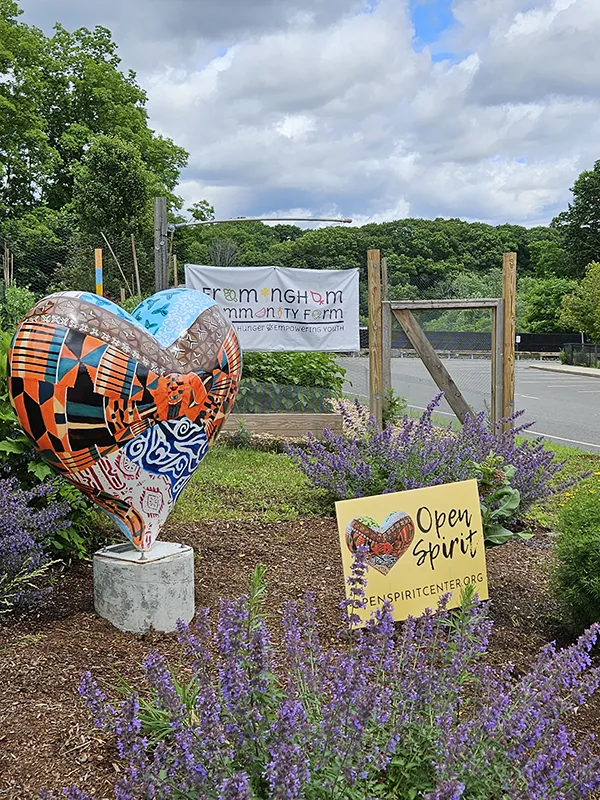 Photo of Open Spirit sign, a heart sculpture, and a sign for the community farm.