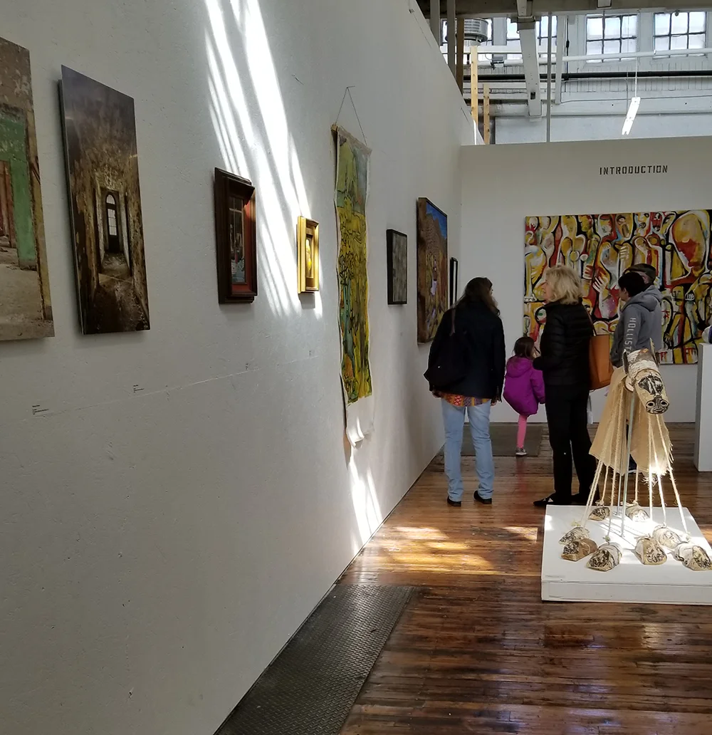 Photo of several people looking at artwork on the walls of a gallery in Saxonville Mills