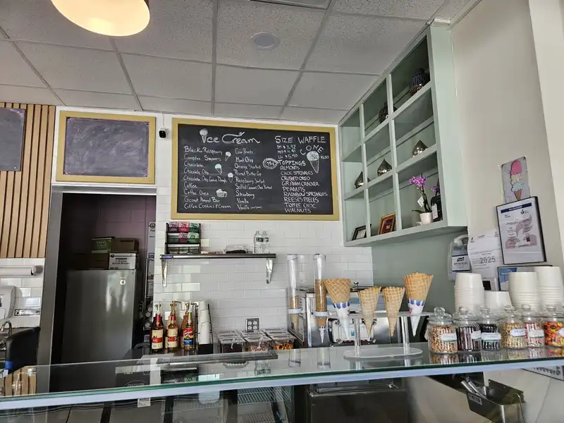 A look at the counter and wall behind with blackboard listing ice cream flavors and toppings
