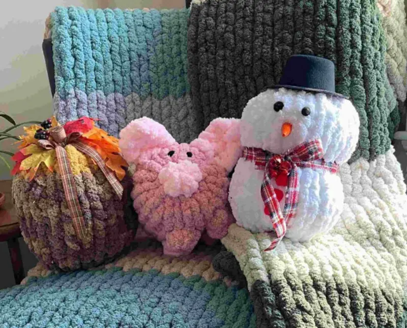 3 cute stuffed plushies on a chair, including a snowman